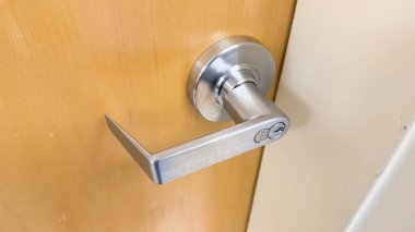 Kilitli beyaz bir kapının metal sapı