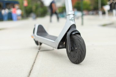 Güneşli bir günde siyah scooterlı bir sokakta scooter.