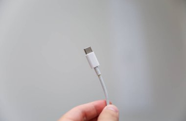 Beyaz arka planda beyaz şarj aleti olan beyaz akıllı telefon.