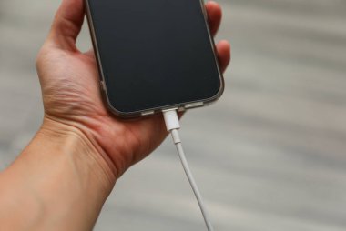 Arka planda kablo ile el ele tutuşan cep telefonu