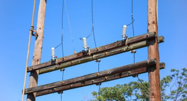 Mavi gökyüzü arkaplanlı eski elektrik direkleri.