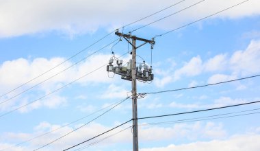 Elektrik hattı ve açık mavi gökyüzü arkaplanlı yüksek voltaj iletisi