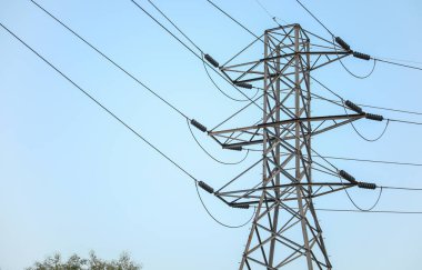 Mavi gökyüzü arka planında yüksek voltajlı elektrik hatları