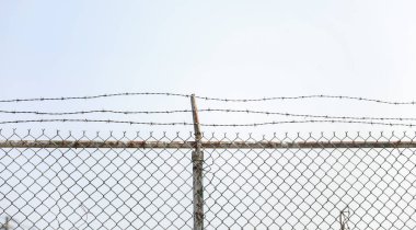 Bulutlu mavi gökyüzü arka planına karşı dikenli tel örgü.