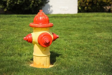 Yeşil çimlerde kırmızı ve turuncu yangın musluğu