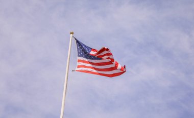 Mavi gökyüzünde dalgalanan Amerikan bayrağı
