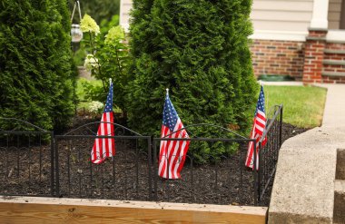 Amerikan bayrakları ve çitin önünde küçük bir ev.