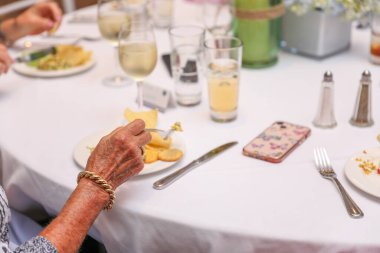 Yemek odasındaki masada oturan yaşlı insanların kırpılmış görüntüsü.