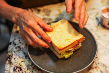 Kadın elleri mutfakta sandviç yapıyor.