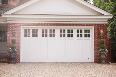 Beyaz, kahverengi, kahverengi tuğla duvarlı ve verandalı beyaz bir evin ön kapısı.