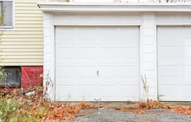 Beyaz tuğlalı kapısı ve turuncu tuğlalı duvarı olan bir garaj.