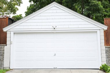 Beyaz kapısı ve mavi tuğlalı duvarı olan garaj