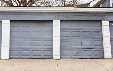 iki gri garaj kapısı, beyaz ve kahverengi boya ve tuğla duvar. Gri tuğlalı duvarı ve beyaz metal çiti olan garaj. konsept