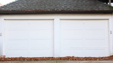 İki beyaz tuğlalı kapısı olan garaj kapıları