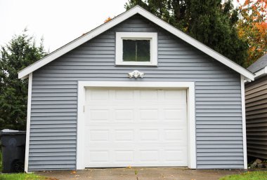 Kahverengi ahşap evi olan beyaz bir garaj.