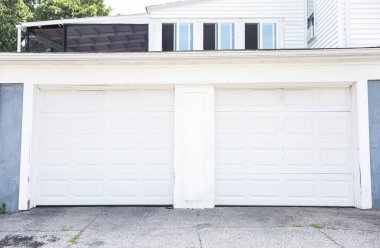 Kapısı, ön kapısı ve garajı olan beyaz tuğlalı bir garaj..