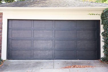 Tuğla binanın ortasında metal kapısı olan siyah bir garaj.