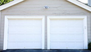 Beyaz boyalı duvarı ve gri tuğlalı duvarları olan garaj kapısı.