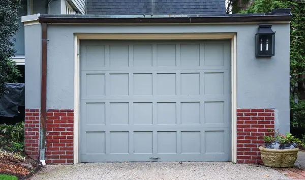 Kahverengi metal kapılı beyaz bir garajın dikey görüntüsü.