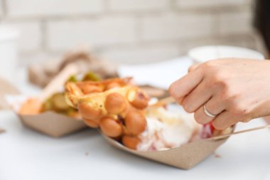 Bir kadın, yanında patates kızartması, yumurta ve tavuk olan plastik bir kutu tutuyor.