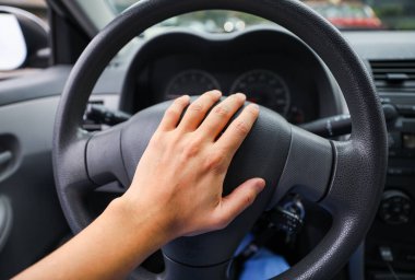 Kadın eli direksiyonda araba sürüyor.