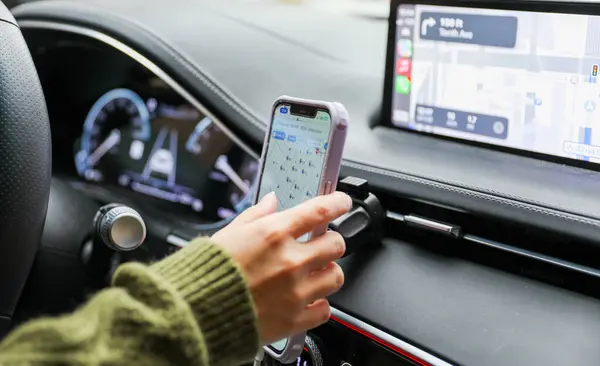 Arabada akıllı telefon kullanan genç bir kadın.