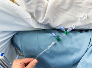 Hastanın ellerinde şırıngayla beyaz üniformalı bir doktor..