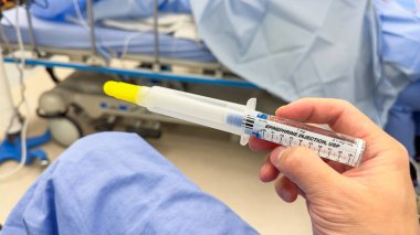 Bir hemşirenin elinde şırınga tutarken.