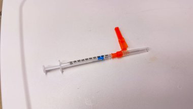 Hastane ortamında steril bir yüzey üzerinde duran temiz sıvıyla dolu tıbbi bir şırınganın yakın çekimi. Sağlık, ilaç ve tedaviyi sembolize eder. Hassasiyet, bakım ve iyileşmeyi temsil eder.