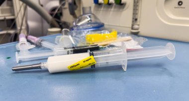 Hastane ortamında steril bir yüzey üzerinde duran temiz sıvıyla dolu tıbbi bir şırınganın yakın çekimi. Sağlık, ilaç ve tedaviyi sembolize eder. Hassasiyet, bakım ve iyileşmeyi temsil eder.