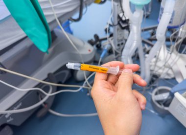 Doktor elinde şırıngayla bir tıp hastanesinde aşı tutuyor..