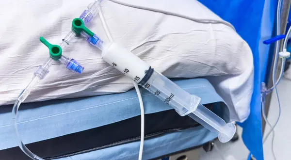 stock image close-up of a medical syringe filled with clear liquid, resting on a sterile surface in a hospital environment. Symbolizing healthcare, medicine, and treatment, it represents precision, care, and healing