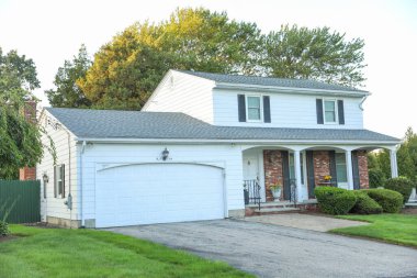 Beyaz tuğla duvarlı, iki garajlı, iki kapılı ve yeşil çimenli yeni modern ev dış görünüşü. Amerika, Amerika