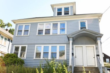 İki penceresi ve mavi gökyüzü olan beyaz bir ev.