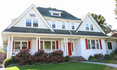 Kırmızı pencereli büyük beyaz bir ev.