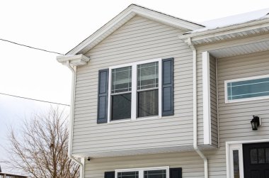 Pencereleri ve mavi gökyüzü olan beyaz tuğlalı ev.