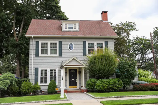 Arka planda iki kırmızı tuğlalı ve yeşil ağaçlı güzel beyaz bir ev.