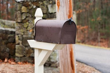 Beyaz tuğla duvarlı çitin üstünde posta mektupları olan posta kutusu