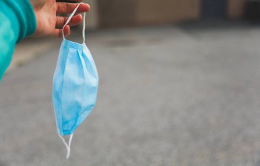 Mavi tıbbi koruyucu maske ve gri arka planda sarı lastik eldivenler..