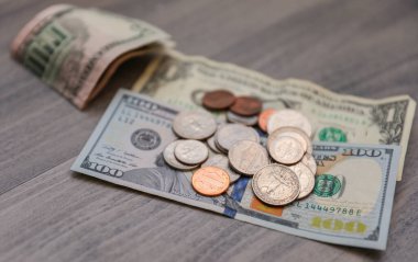 Dolar banknotları ve paralar ahşap arka planda.