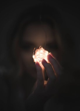 Kadın eli siyah arka planda kristal bir küre tutuyor.