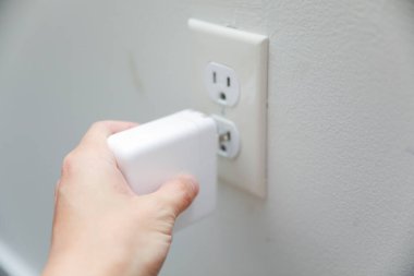 Odadaki duvarın fişini elinde tutan kadın. Enerji kaydet.
