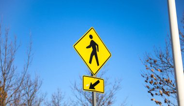 Sarı çizgili ve mavi gökyüzü olan yaya geçidi tabelası.