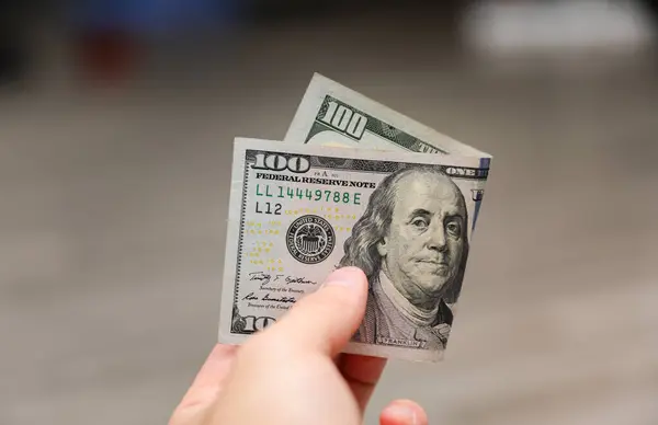 100 dolar elinde, ahşap bir masanın üzerinde, yakın plan -