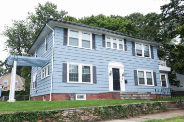 Mavi gökyüzü ve beyaz çitli beyaz bir evin mavi renginde bir ev..