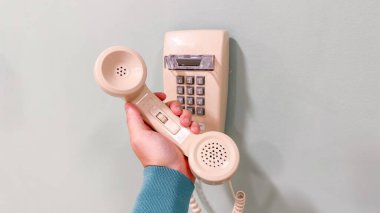 Beyaz arka planda telefon tutan bir kadın eli.