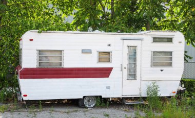 Bahçesinde kırmızı çatı olan büyük beyaz bir karavan.