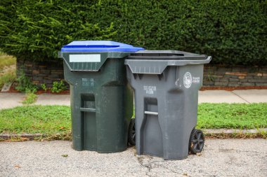 Sokakta iki plastik çöp kutusu var.
