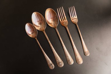 Siyah arka planda gümüş çatal bıçak seti.