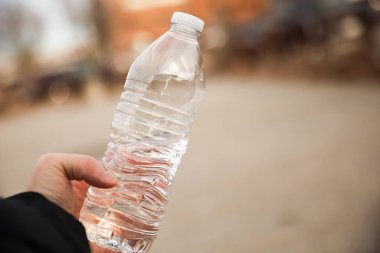 Elinde plastik su şişesi tutan adam.
